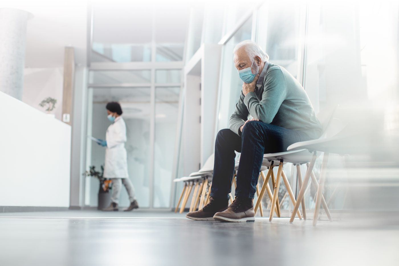 An older adult waiting alone in a clinic, underscoring the growing care gap